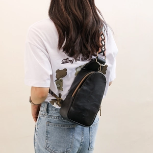 Detail of black PU leather chest bag with a wide colorful geometric pattern woven strap