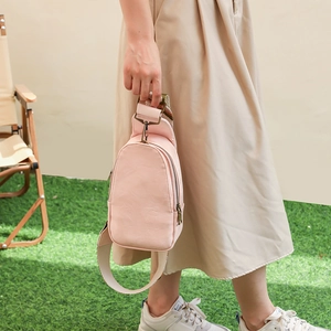 Detail of pink PU leather chest bag with retro metal zipper and wide woven strap