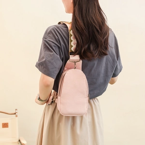 Detail of pink PU leather chest bag with decorative wide jacquard strap and vintage zippers