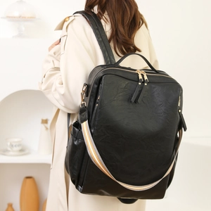 Seitenansicht eines schwarzen Lederrucksacks mit gestreiftem Gurt an einer Schulter