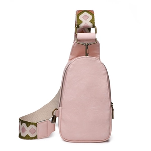 Pink faux leather chest bag with a wide geometric patterned shoulder strap on white background