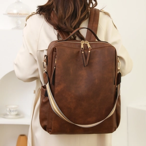 Detail eines dunkelbraunen Vintage PU-Lederrucksacks mit Ziergurt und Doppelreißverschlüssen