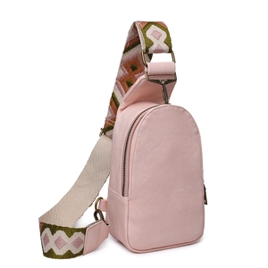 Close-up of pink PU leather sling bag with bohemian style wide woven strap and bronze hardware
