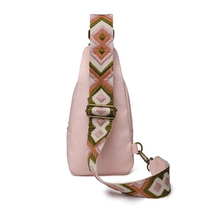 Close-up of pink PU leather chest bag with a wide geometric woven shoulder strap
