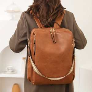 Brown leather backpack for women with striped handle shown in a stylish lifestyle setting
