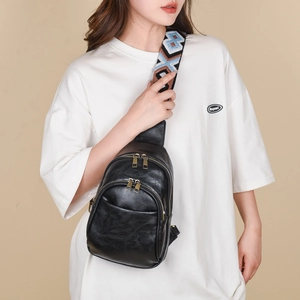 Detail of black PU crossbody bag featuring dual zippers and a geometric ethnic woven strap