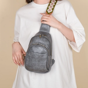 Detail of grey vintage leather crossbody bag with colorful woven geometric shoulder strap