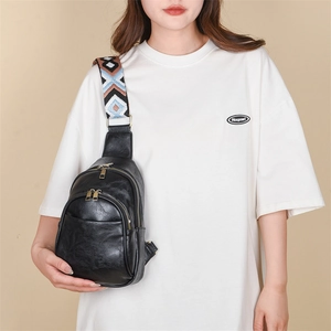 Detail of black PU leather chest bag with multi-zipper pockets and ethnic woven strap