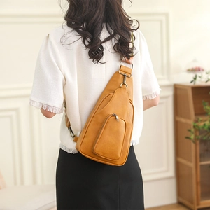 Close-up of retro PU leather sling bag with colorful geometric woven strap and bronze hardware