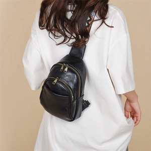 Detail of black PU leather chest bag with retro geometric strap and bronze zippers