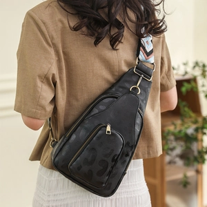 Close-up of black leopard print chest bag with vintage embroidered wide strap on model