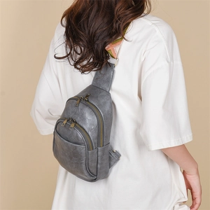 Close-up of grey vintage PU leather chest bag featuring ethnic embroidered shoulder strap