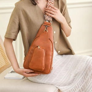 Brown faux leather chest bag with ethnic pattern wide strap shown on crossbody model