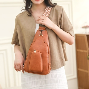 Brown faux leather crossbody bag with geometric woven strap worn by a female model
