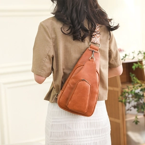 Close-up of brown PU leather crossbody bag featuring a tribal pattern woven wide strap