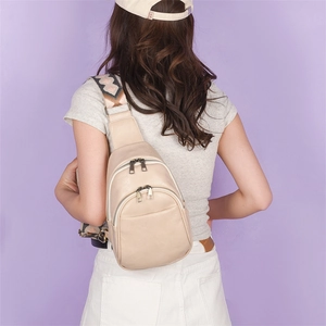 Close-up of beige faux leather chest bag with ethnic strap and gold metal zippers