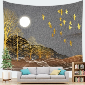 Artistic wall tapestry with golden trees and birds hanging over a modern grey sofa