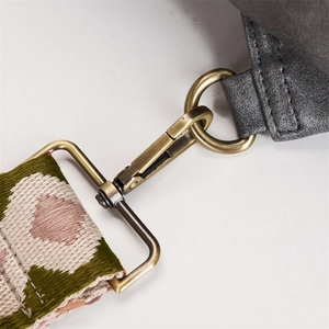 Detail of vintage bronze hook and patterned woven strap on grey textured backpack