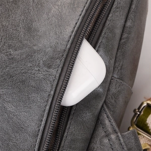Detail of grey vintage PU leather texture and zipper pocket with wireless earbuds case