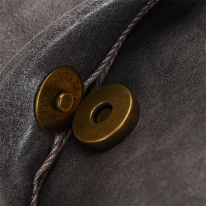 Macro view of bronze magnetic clasp on dark grey frosted leather backpack detail