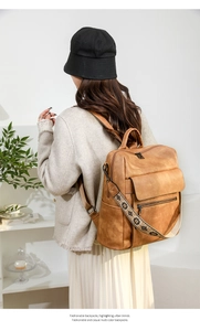 Brown leather backpack with floral embroidered strap shown on a model in a lifestyle scene