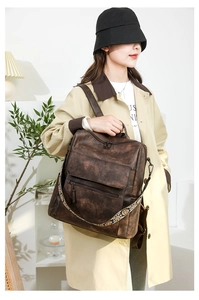 Detail view of brown vintage backpack with textured leather and bohemian woven strap