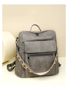 Close-up of gray pebble leather backpack with ethnic embroidery shoulder strap