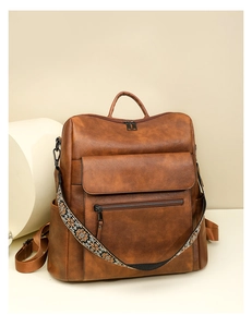 Detailed macro view of the vintage brown faux leather backpack with floral jacquard strap
