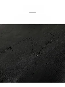 Detail of waterproof black PU leather with lychee texture and water droplets on surface