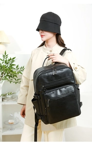 Side view of a large black leather backpack worn by a model in a bright studio