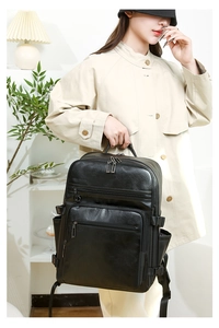 Detail view of a black leather business backpack showing multiple zipper compartments and side buckles