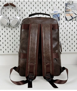 Detailed back view of vintage brown backpack with wide shoulder straps and top handle