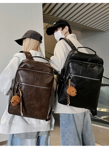 Detail of vintage multi-pocket backpack with plush bear charm on escalator