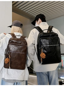 Detail view of large retro leather backpacks in black and brown worn by models outdoors