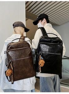 Detail of vintage multi-pocket backpacks in black and brown leather with teddy bear charms