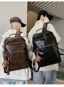Detail of vintage PU leather backpack with multiple pockets and plush pendant accessory