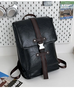 Detail of the black leather backpack with brown straps and silver metal buckle closure