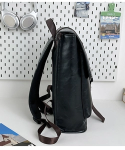 Detailed side view showing textured black leather backpack and durable nylon shoulder straps
