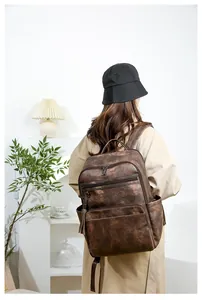 Rear view of a vintage brown leather backpack with multiple zip pockets on a female model
