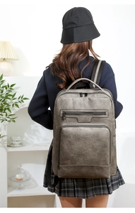 Detailed back view of a charcoal gray PU leather business backpack worn by a person indoors
