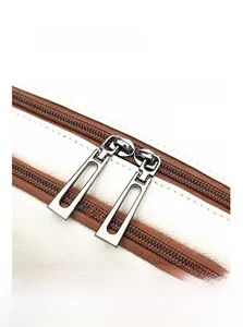 Close-up of durable two-way gunmetal zippers on a white pebble grain leather backpack