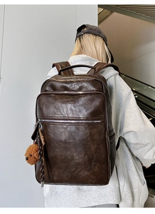 Close-up of retro brown multi-pocket backpack with cute bear pendant in a modern setting