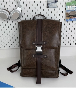 Detail of vintage brown leather backpack featuring metal buckle and textured flap design