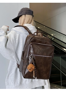 Detail of vintage brown leather backpack with multiple pockets and cute plush charm