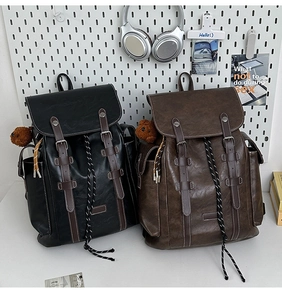 Detail of vintage PU leather backpacks with flap buckles and plush bear pendant detail