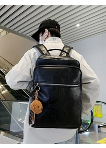 Detail view of large black textured leather backpack with multiple zip pockets on model