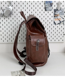 Close-up of vintage brown leather backpack showing side pocket and white contrast stitching