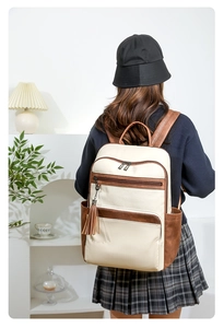 Detail of minimalist cream and brown leather backpack with tassel and side pockets