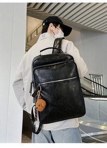 Detail of black leather backpack with metal zippers and cute brown bear charm