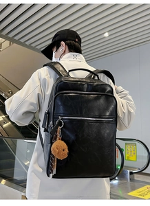 Detailed street shot of a vintage multi-pocket black leather backpack with a teddy bear charm